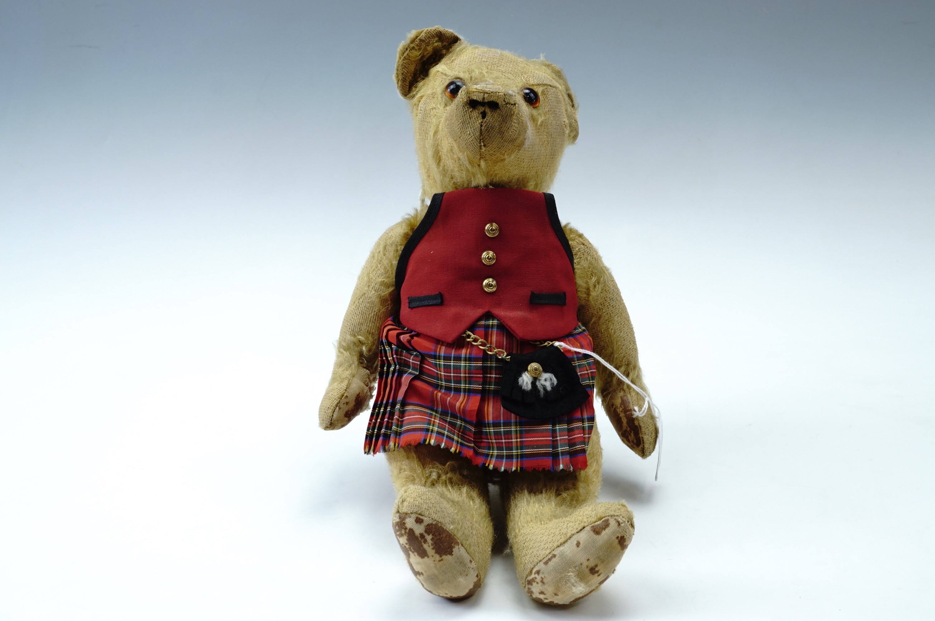 A late 19th / early 20th Century articulated mohair Teddy bear, having glass eyes, wearing a later
