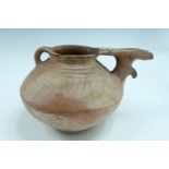 An ancient Luristan earthenware spouted vessel, of lenticular form with bridged spout and opposed