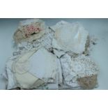 A large quantity of vintage tablecloths and doilies together with a christening gown etc
