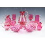 A quantity of 19th Century cranberry glass, comprising various jugs, two suites of cream jugs and