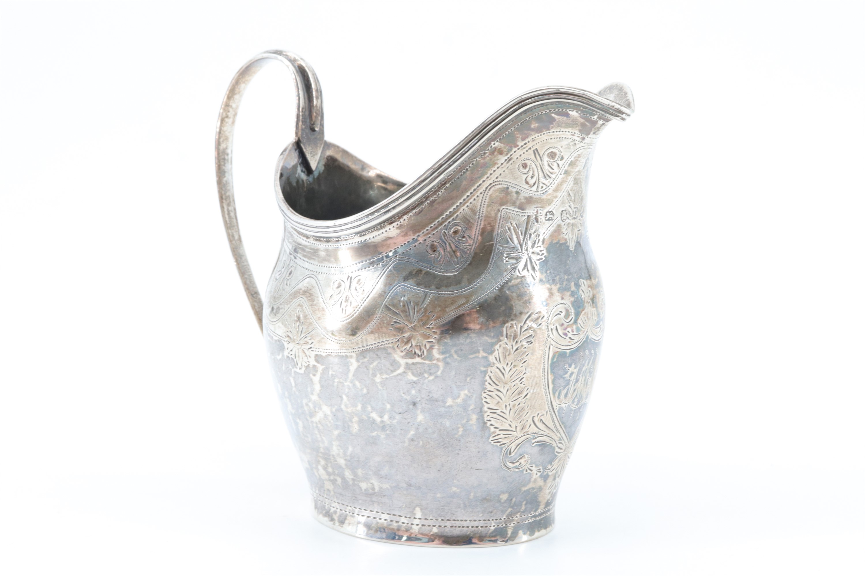 A Georgian silver cream jug, having bright cut decoration and a shield bearing a monogram to the