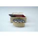 A child's vintage electroplate mounted hair brush and comb cased set, the brush back decorated in