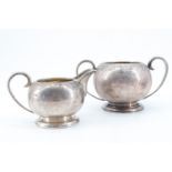 A Garrard and Co silver cream jug and sugar basin, decorated with winged masks among scrolls,