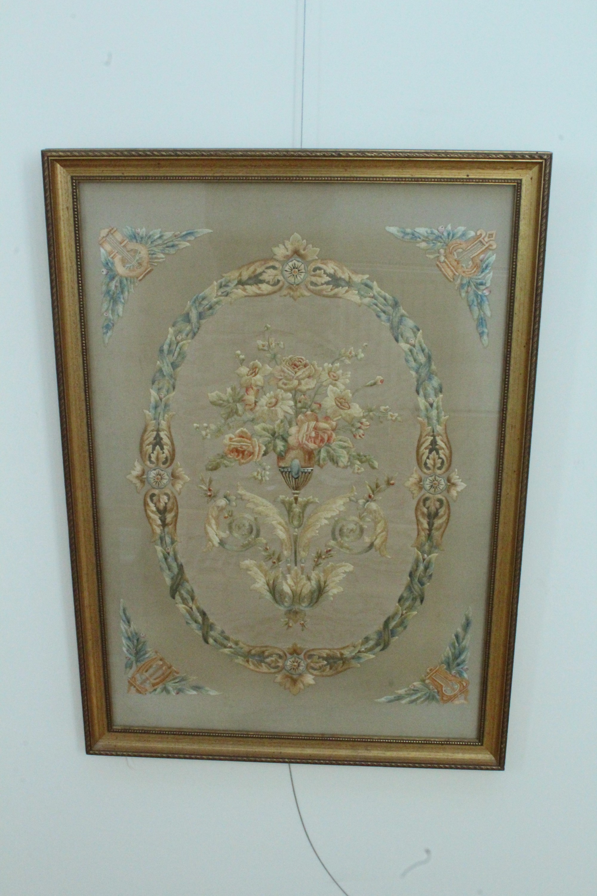 An early 20th Century embroidered silk panel, depicting a stylized urn with flowers, above