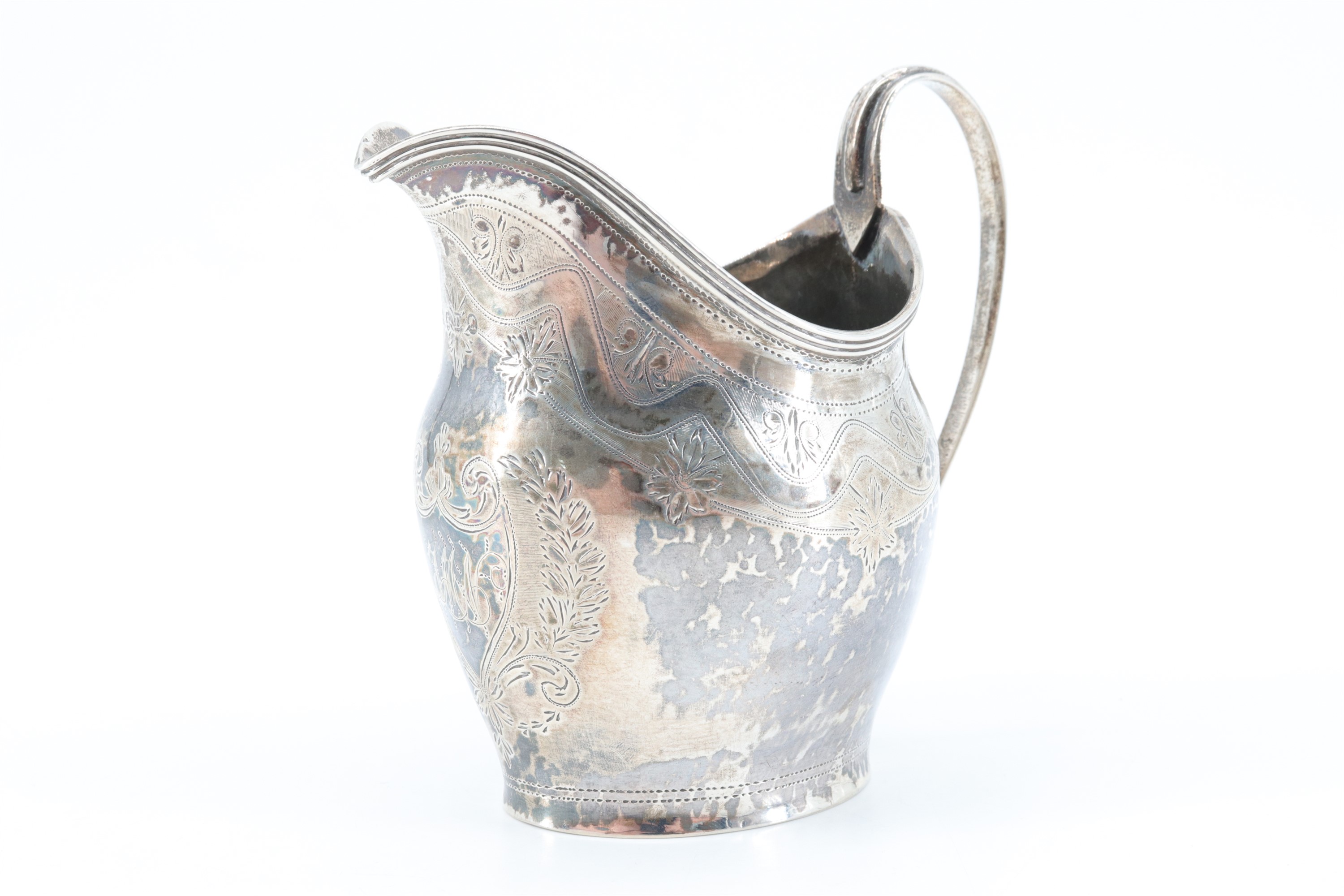 A Georgian silver cream jug, having bright cut decoration and a shield bearing a monogram to the - Image 2 of 4