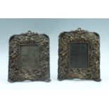 A pair of 19th Century easel back copper photograph frames, each joyfully decorated with putti among