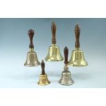 A Victorian brass hand bell, having a turned mahogany handle, together with four other bells