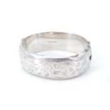A floral engraved silver bangle, hinged with a box clasp, (a/f), Birmingham, 1972, 33 g, 6 x 5.3