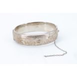 An Elizabeth II silver bangle, bright cut decorated, hinged with a box clasp, bearing '12-12-74'