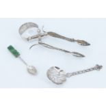 A set of white metal filigree tongs, together with a Mexican white metal spoon and a Middle