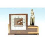 A 1950s Moderne oak cased figural mantle clock, having a three train movement striking and chiming