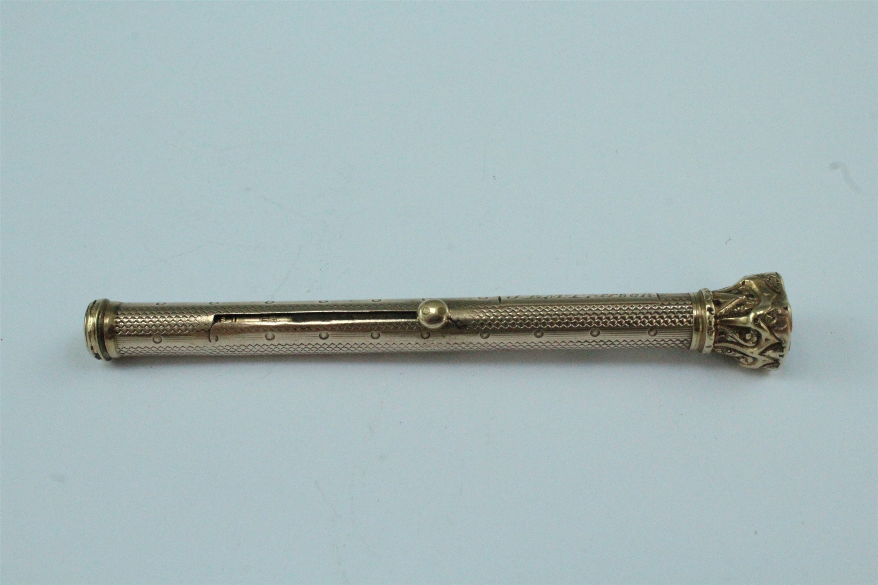 A yellow metal combination propelling pencil and dip pen, having an engine turned barrel and a
