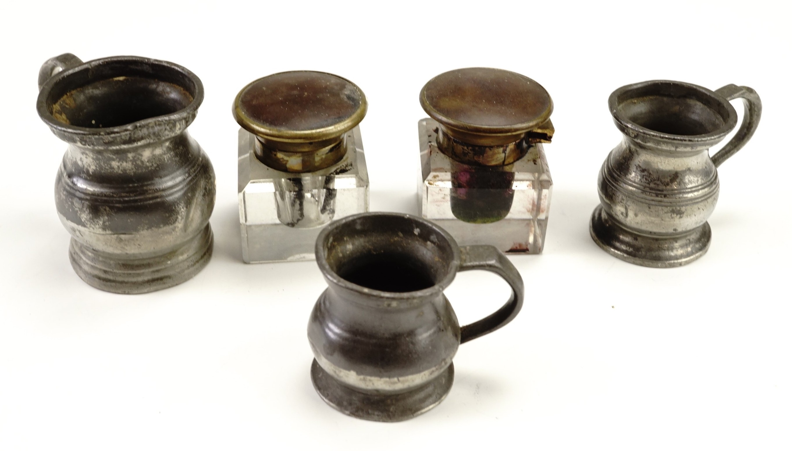 Two late 19th / early 20th Century glass ink wells together with three pewter baluster measures