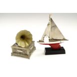 Two novelty petrol table lighters, comprising a tinplate model yacht on a plastic base, and a