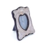 An Art Nouveau influenced diminutive silver photograph frame, having a silver front with embossed