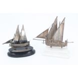 Two silver models of Maltese speronara two masted boats, respectively standing on a white painted