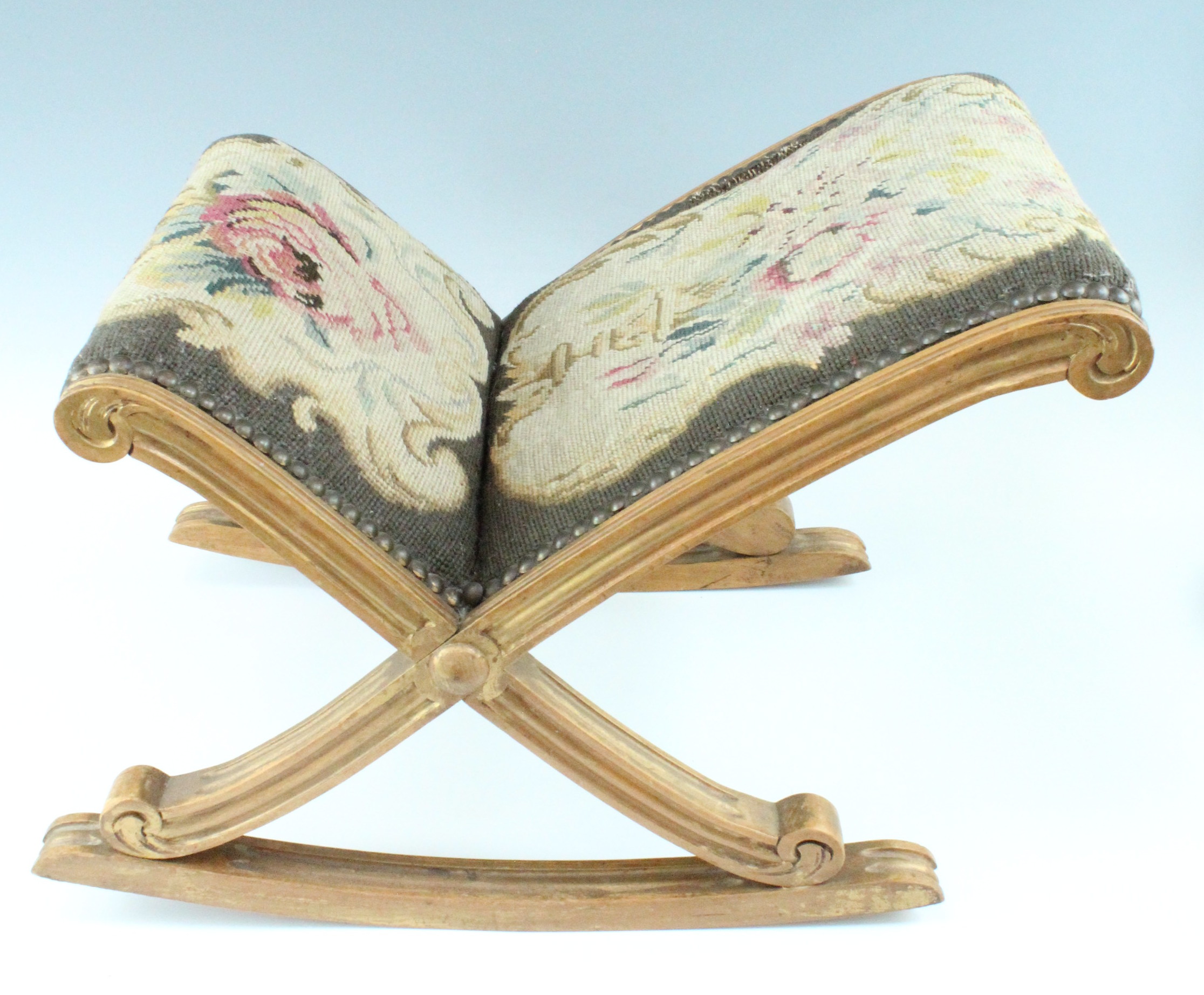 An old reproduction tapestry-upholstered giltwood gout stool