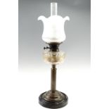 A Victorian brass columnar oil lamp, having a cut glass reservoir and a frosted glass shade, on a