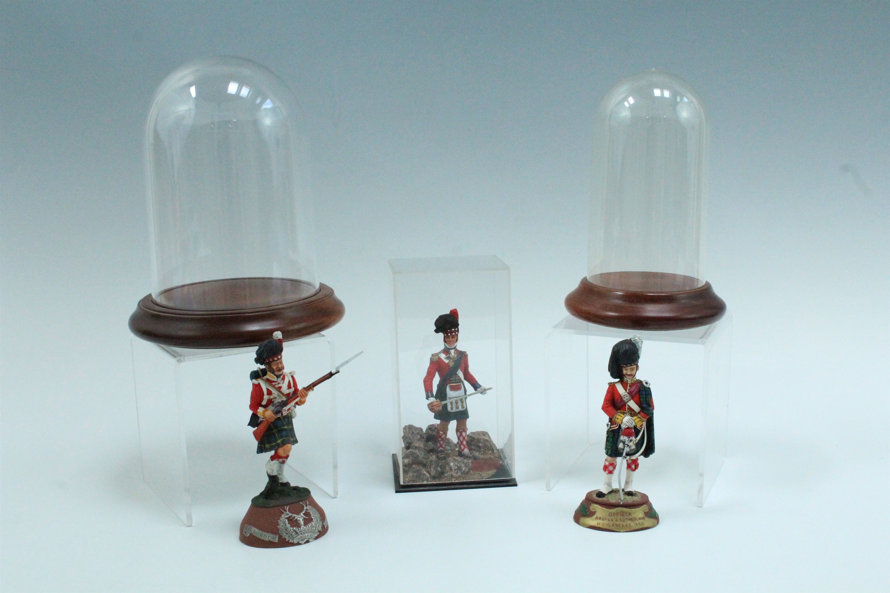 Three painted die-cast lead figures of 19th Century Highland soldiers, one in display case, together