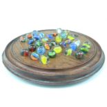 A turned oak solitaire board, together with a quantity of marbles