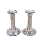 A pair of Edwardian silver candle holders, of unadorned columnar form, Chester, 1906, weighted, 12