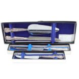 Four boxed 1970s silver handled Queen's pattern serving implements, comprising cake knife, cheese