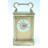 An early 20th Century brass carriage clock, the gilt face embossed with scrolling flowers, having