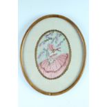 A 1920s framed embroidery of a girl wearing a bonnet and holding a bunch of daisies, under glass