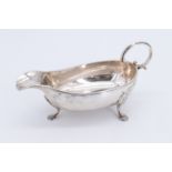 A late Victorian silver sauce boat, having three shell form pad feet and a C-scroll handle,