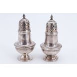 A near pair of late Victorian silver baluster pepperettes, (the pedestal bases differ slightly),
