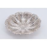 An Edwardian silver bowl, of fluted petal form, repousse decorated with flowers and fruit,