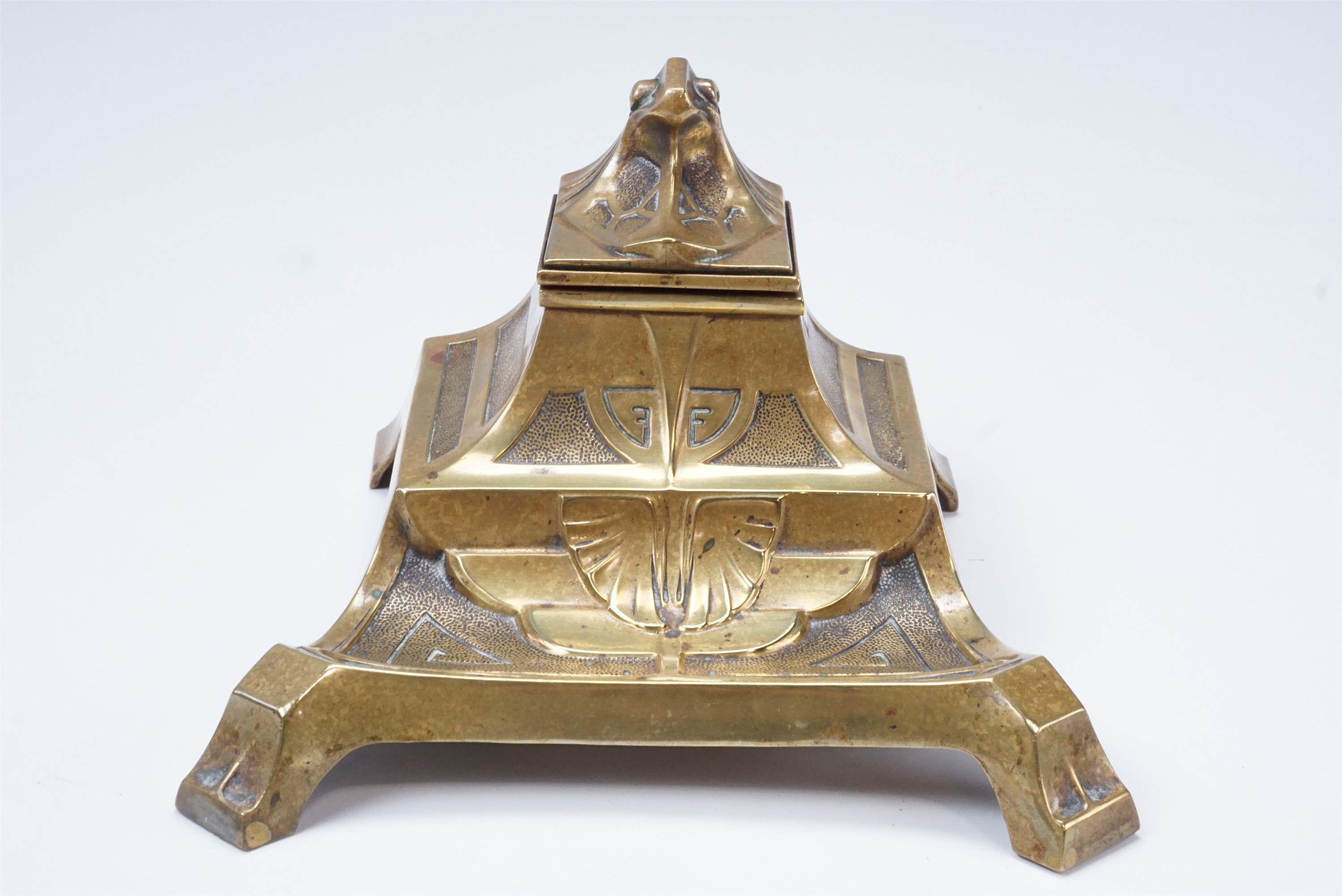 A Jugendstil cast brass standish, having a single inkwell with a stylized eagle's head cover, on a