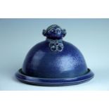 A modern stoneware cheese dome, in blue sponge glaze and having a handle modelled as a Dutch lady'