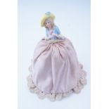 A 1930s porcelain and fabric pin cushion lady, 18 cm