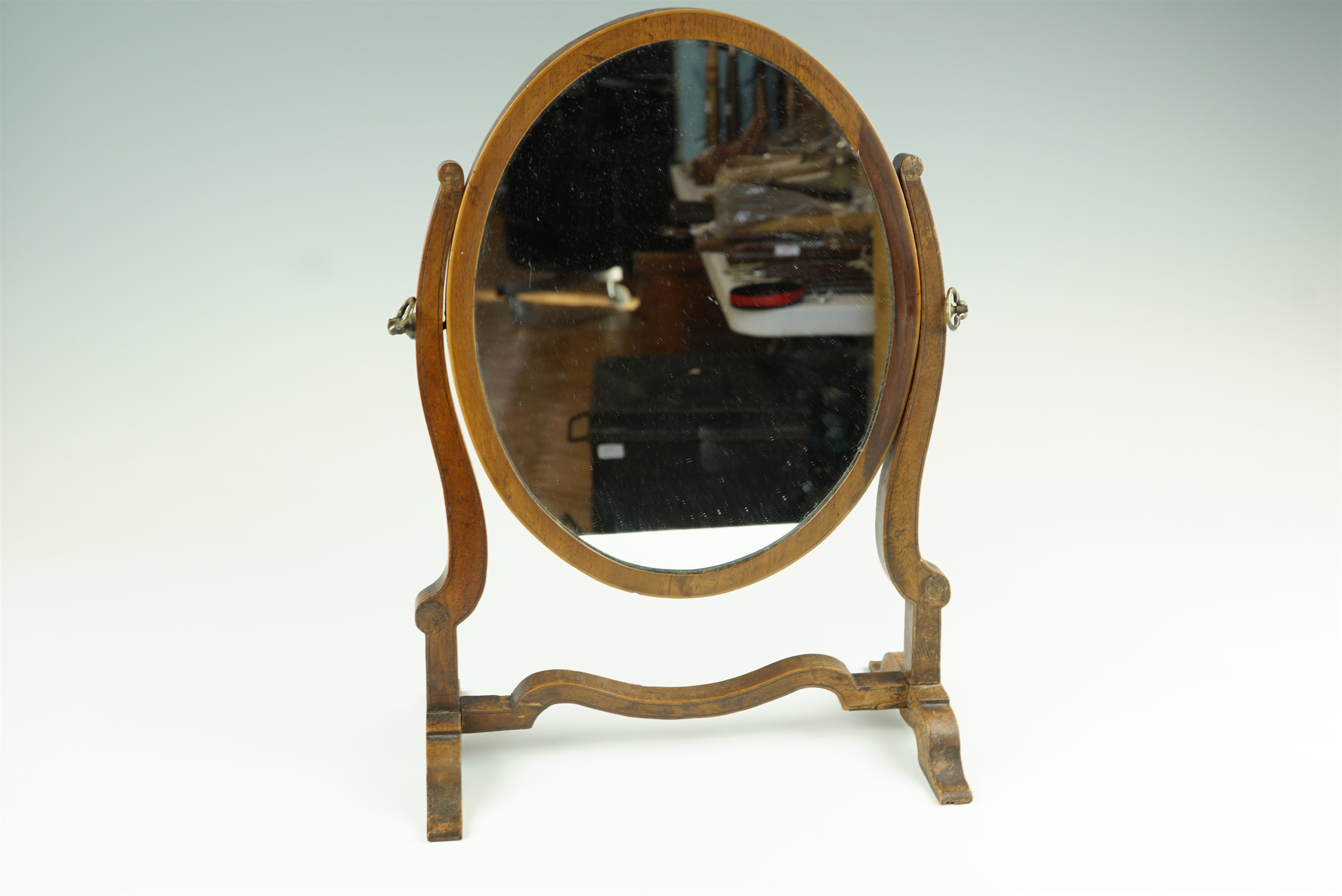 A 19th Century mahogany oval swivel toilet mirror, 27 cm x 37 cm