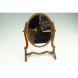 A 19th Century mahogany oval swivel toilet mirror, 27 cm x 37 cm