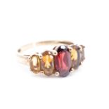 An almandine and citrine dress ring, having an oval garnet (9 x 5 mm) between four graduated