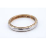 A 1970s 18 ct gold and platinum wedding band, having a faceted surface with engraved sides,