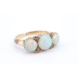 A handsome three-stone opal and diamond ring, comprising three circular opal cabochons of 7 mm and 6