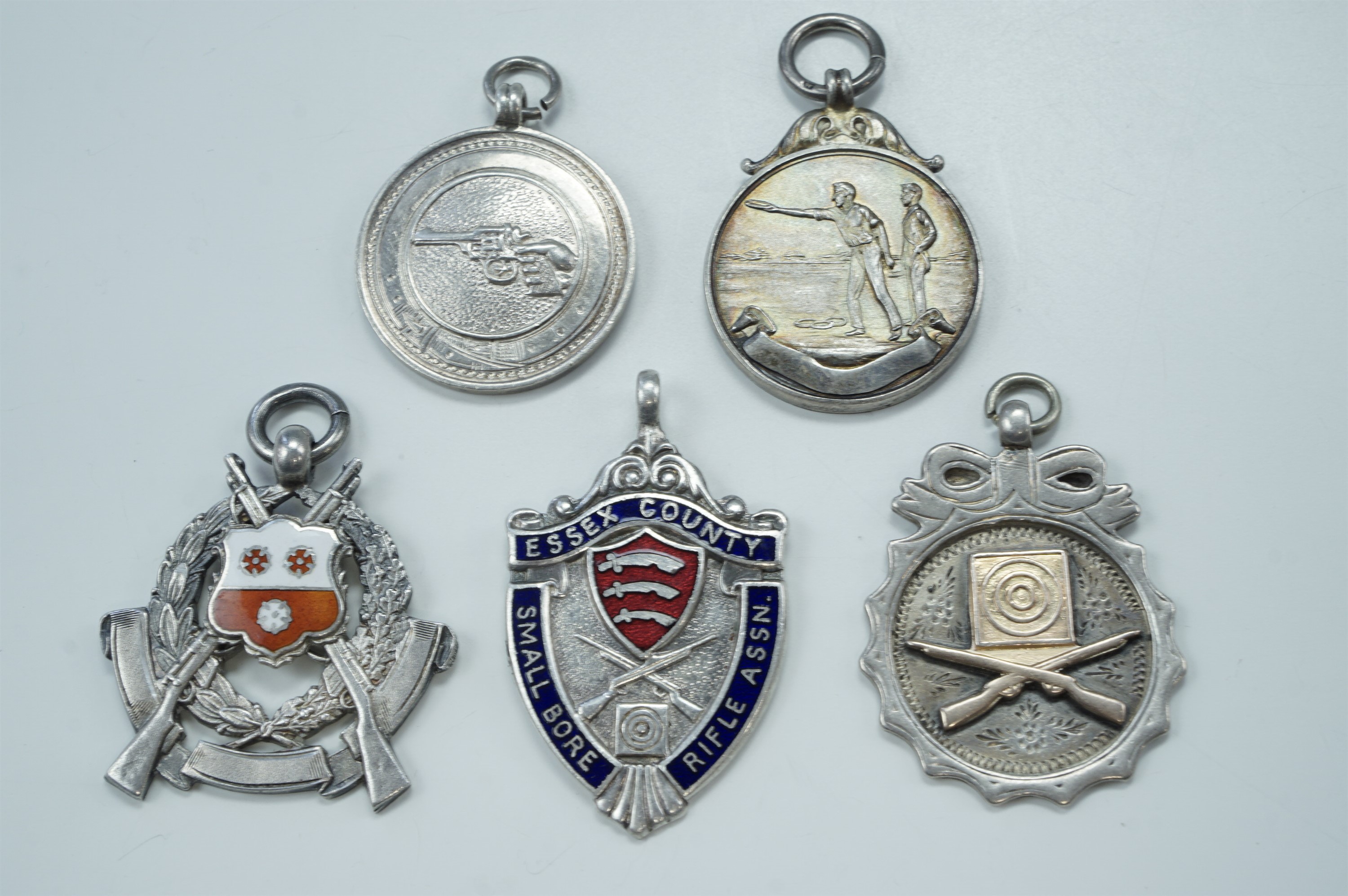 Three 1930s silver target shooting fob medals, a white metal medal, and two enamelled electroplate