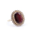 A late 20th Century garnet and diamond dress ring, having an oval garnet (13 x 9 mm), in a multi