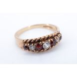 A lady's red and white garnet finger ring, having three graduated white brilliants between four
