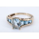 A striking blue spinel 9 ct gold dress ring, having a central baguette (6 x 8 mm) in a four prong