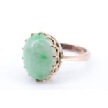 An early 20th Century lady's jade finger ring, having a oval jade cabochon (11 x 13 mm) set on a