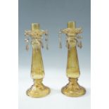 A pair of pressed amber glass candlesticks, having detachable bobeches and pendant drops, 31 cm