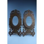 A pair of early 20th Century Chinese carved wood swivel picture frames, each having a dragons and