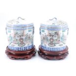 A pair of late Quing Chinese famille rose covered cylindrical jars, each having a domed lid with