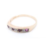 A modern ruby, diamond and 9 ct gold ring, having three diamonds between four rubies channel set
