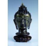 A cast brass Buddha bust on a wooden stand, overall 23 cm