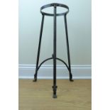 A modern brass mounted wrought iron tripod stand, having curved stretchers meeting at a brass